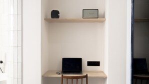 A workspace with a laptop on a shelf, a chair, and a framed item on the wall. - Mouchki (Marseille)