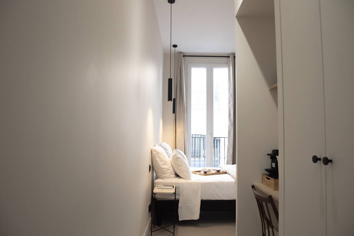 Ein Schlafzimmer mit einem Bett, einem Nachttisch und einem Fenster mit Vorhängen.