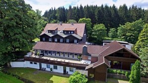 A two-story building with a sloped roof, multiple windows, and a covered outdoor area. - Ferienhaus im Kurort inkl. Frühstück (Goslar)