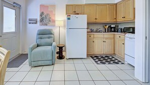 A compact kitchen with wooden cabinets, a white refrigerator, a microwave, and a stove. - Directly on the Gulf - Unit  4 - 1 Bedroom - Ground Floor - Sleeps up to 6] (Venice)