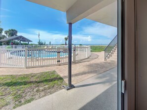 A pool area with a fenced deck, a flag, and a view of the beach.