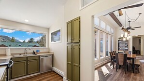 Una cocina moderna con vistas a montañas, un comedor con candelabro y un ventilador de techo.