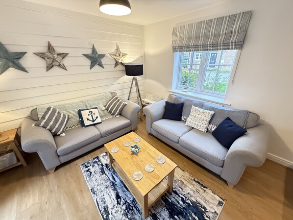 A living room with two grey sofas, a wooden coffee table, and decorative star wall art. - Stunning Coastal Cottage - Sleeping 6 in 3 Bedrooms - Pool and Beach Access Included. (Filey)