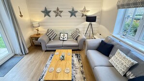 Una sala de estar con un sofá gris, una mesa de centro de madera y una lámpara.