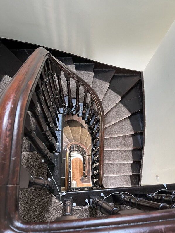 A wooden staircase with a handrail and a view of a room at the top.