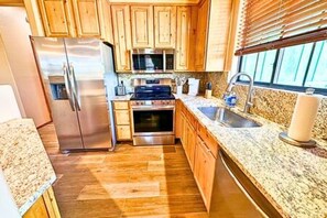 A compact kitchen with wooden cabinets, stainless steel appliances, and a granite countertop.