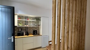 Una cocina moderna con armarios blancos, microondas, cafetera y refrigerador.