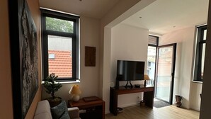 Una sala de estar moderna con un sofá, un televisor y piso de madera.