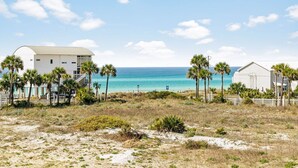 A beachfront property with a white building, palm trees, and a view of the ocean. - Relax in Style Steps to the Beach • Heated Pool, Gulf Views, & Room for Everyone (Inlet Beach)