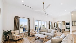 A spacious living room with a large sofa, armchairs, a coffee table, and a ceiling fan. - Relax in Style Steps to the Beach • Heated Pool, Gulf Views, & Room for Everyone (Inlet Beach)