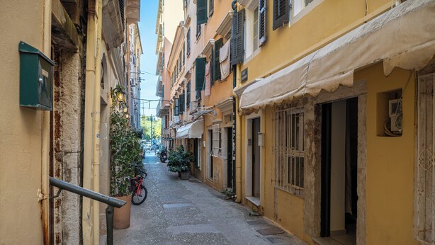 Una calle estrecha flanqueada por edificios, una bicicleta y un árbol de Navidad.