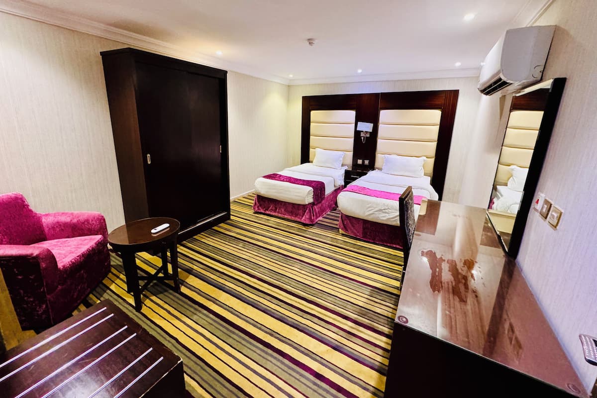 A hotel room with two beds, a desk, a chair, and a large mirror.