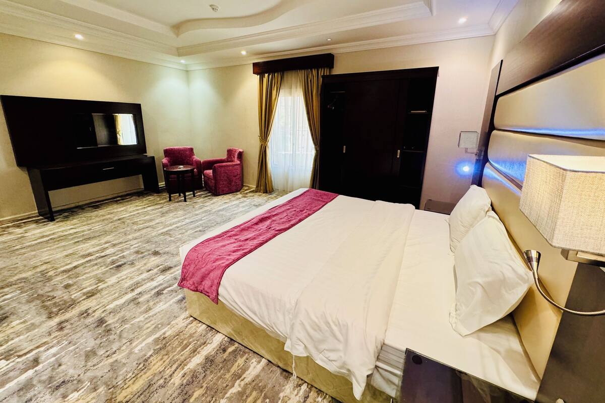 A hotel room with a large bed, a TV, a desk, and two chairs.