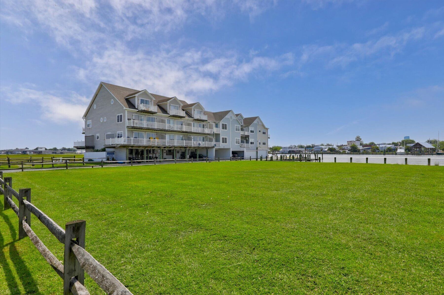 A large, multi-story building with a flat roof and multiple balconies, situated near a body of water.
