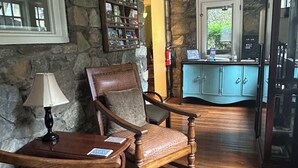 Una habitación acogedora con pared de piedra, muebles de madera, una estantería y vistas a través de una ventana.