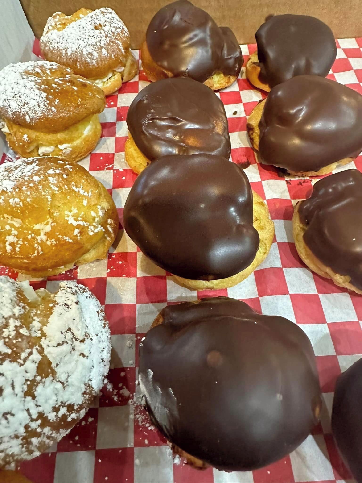 A variety of doughnuts on a checkered paper surface.