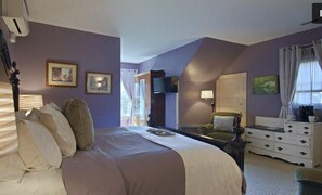 A bedroom with a large bed, a dresser, a television, and framed pictures on the wall. - North Lodge Bed & Breakfast (Asheville)