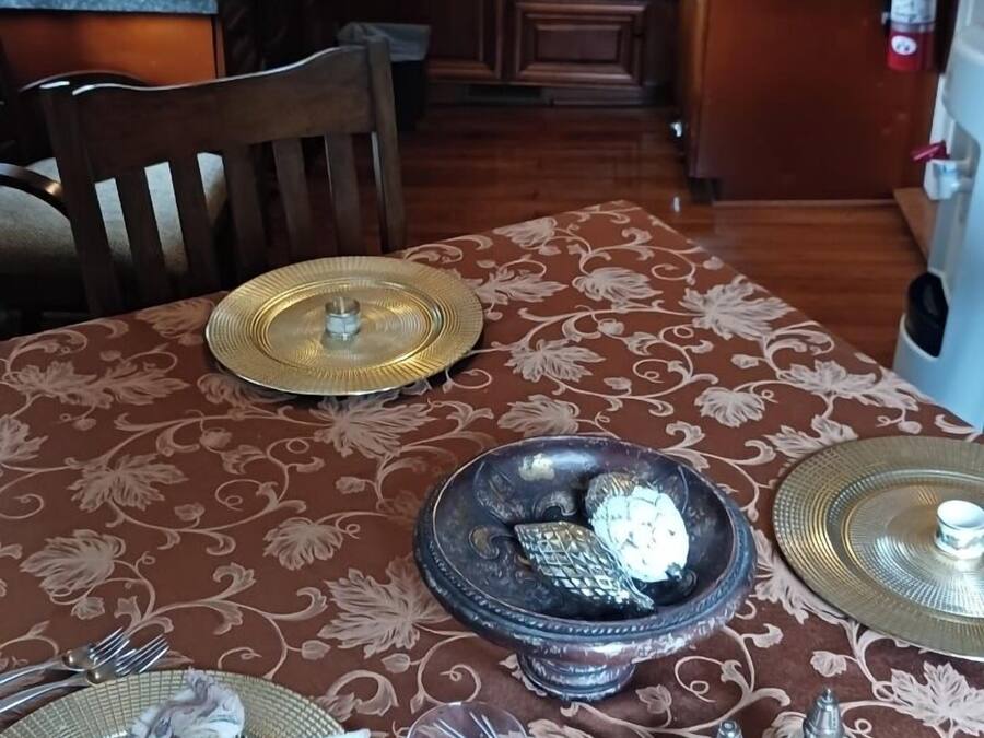 Un comedor con una mesa preparada para dos personas, un refrigerador y un microondas al fondo.