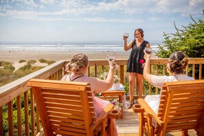 A wooden deck with chairs overlooking a beach.