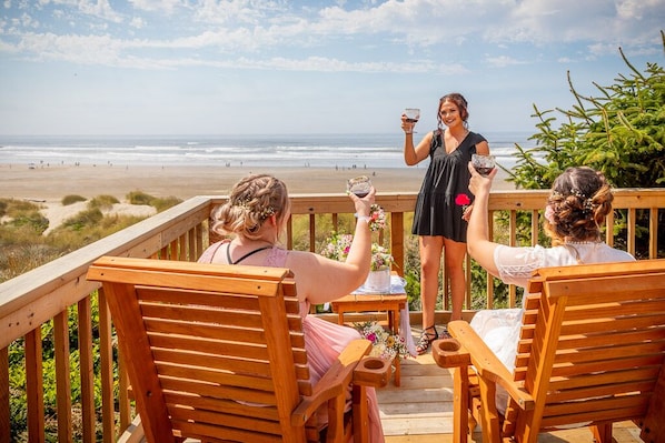A wooden deck with chairs overlooking a beach.