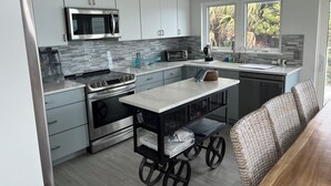 Una cocina moderna con electrodomésticos de acero inoxidable, un microondas integrado y una ventana con vistas al exterior.