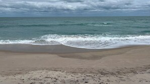 Una playa con olas que acarician suavemente la orilla bajo un cielo nublado.