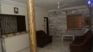 Una sala de estar con dos sofás, una mesa de centro, un pilar decorativo, un reloj y una pared con textura.