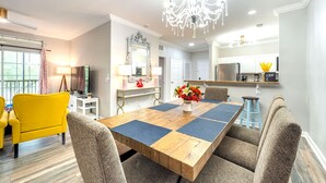 A dining area with a wooden table, cushioned chairs, and a chandelier. - Splendid Renovated 2 + 2 Condo Near Disney with Amazing Amenities (Davenport)