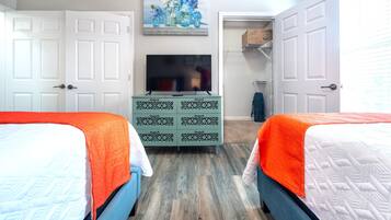 A bedroom with two beds, a dresser, a television, and a closet.