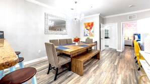 A dining area with a wooden table, benches, and chairs. There is a chandelier above the table. - Splendid Renovated 2 + 2 Condo Near Disney with Amazing Amenities (Davenport)