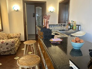 A kitchen with a bar area, stools, a sink, and a countertop with various items.