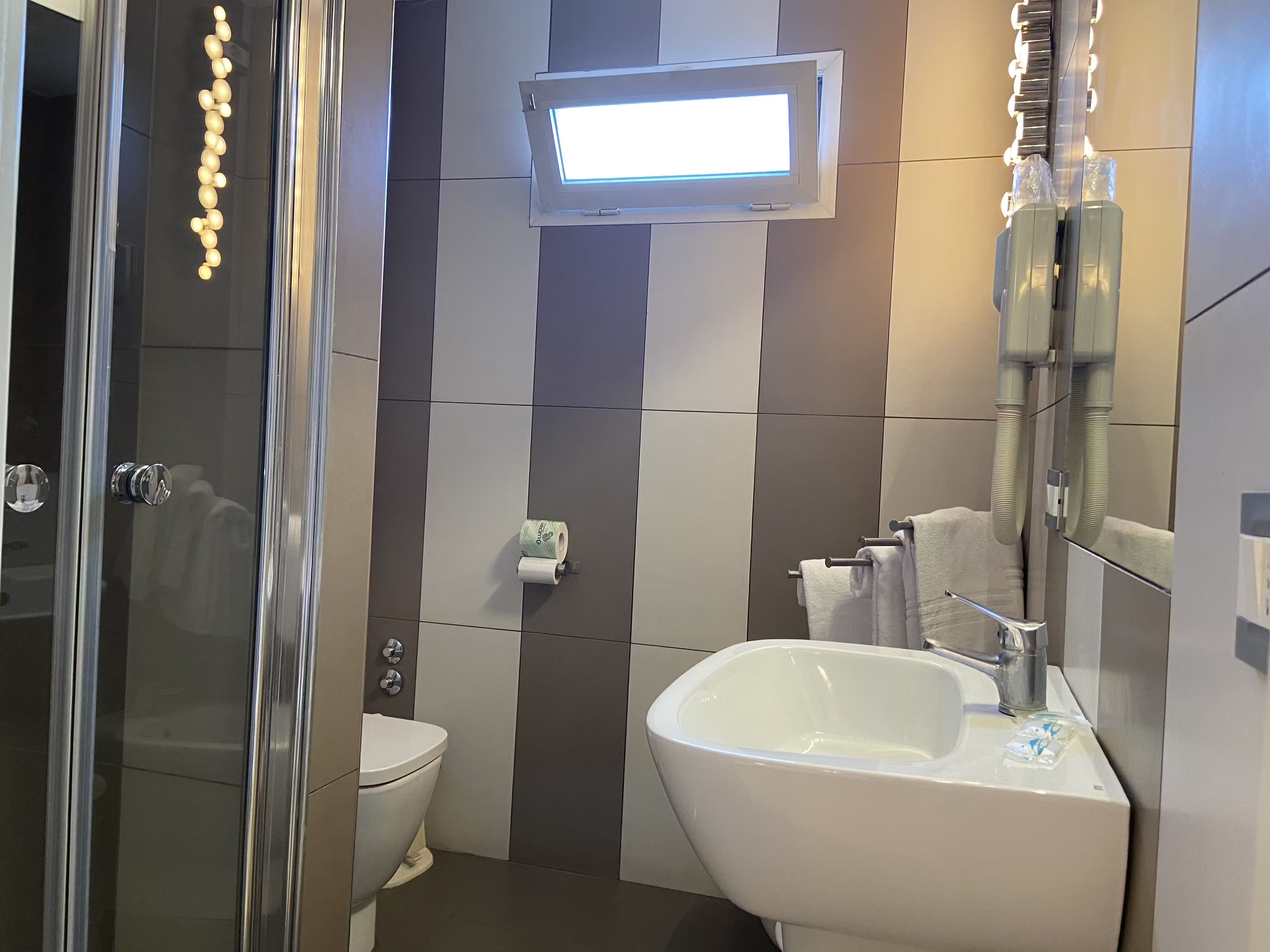 Une salle de bain moderne avec une douche à parois de verre, des toilettes, un bidet et un lavabo avec un miroir.
