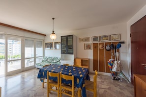 A dining area with a table set for four, a cabinet, and a coat rack with umbrellas. - Spacious Flat With sea View Terrace - Beahost (San Michele al Tagliamento)