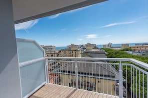 A balcony with a view of a coastal cityscape, including buildings and the sea.
