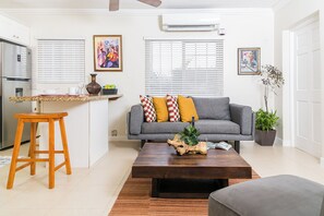 A modern living room with a grey sofa, wooden coffee table, and a small wooden stool. - Charming Studio With Garden Oasis in Kingston (Kingston)