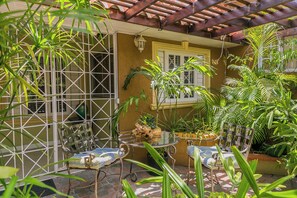 A covered patio with a table and chairs, surrounded by potted plants and a wooden pergola. - Charming Studio With Garden Oasis in Kingston (Kingston)