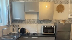 Eine kleine Küche mit Waschmaschine, Herd, Backofen und Kühlschrank.