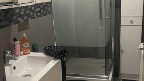 Ein Badezimmer mit Duschkabine aus Glas, Toilette, Waschbecken und Schrank.