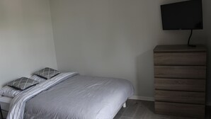 A bedroom with a bed, a dresser, and a TV mounted on the wall. - Charmant Appartement Annecy Avec Vélos et Parking Classé 3 Étoiles (Annecy)