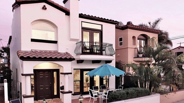 A two-story house with a balcony, a patio with outdoor furniture, and a small garden area. - Beauty by the Beach Socal Fun! (Long Beach)