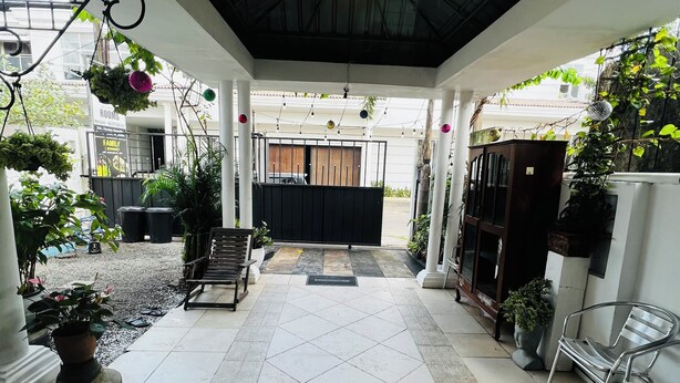 A covered outdoor area with tiled flooring, potted plants, and hanging decorations. - Ramlyn Guesthouse Negombo (Negombo)
