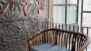 A wooden bench with a glass table in front of a textured wall with floral carvings. - Ramlyn Guesthouse Negombo (Negombo)
