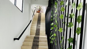 A staircase with a black railing, a welcome mat, and a potted plant at the top. - Ramlyn Guesthouse Negombo (Negombo)