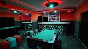 A billiards room with a pool table, stools, and a bar area with shelves of bottles. - Room-deluxe Double Bed Bedroom in Lome - (Lomé)