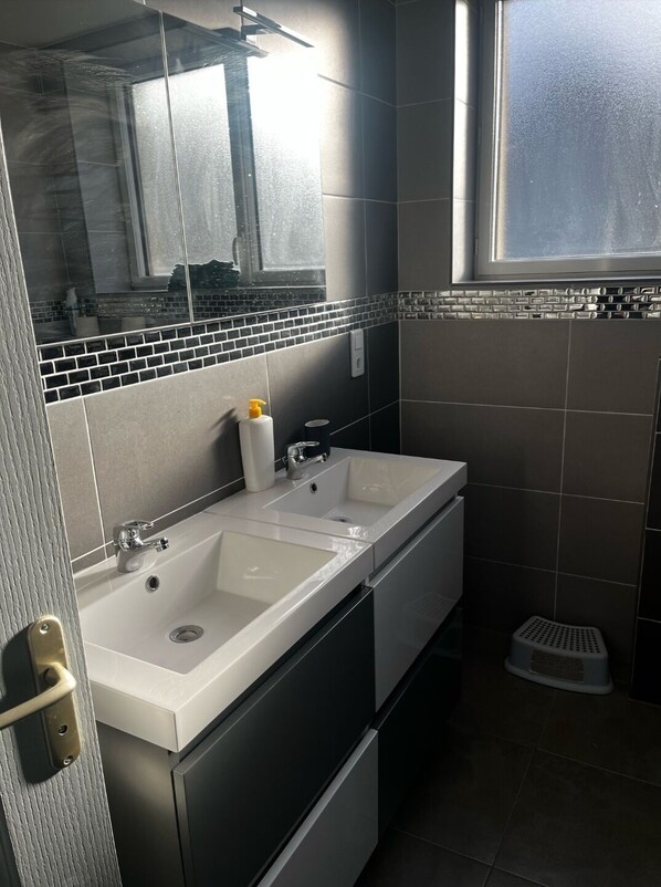 Une salle de bain moderne avec un double vasque, un miroir et une fenêtre.