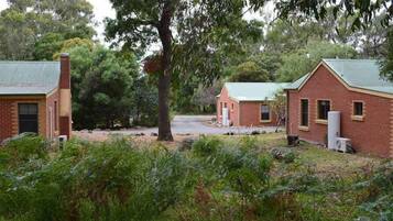 Escape to a serene wooded haven surrounded by lush greenery and two charming buildings with pitched roofs.