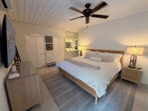 Ein Schlafzimmer mit einem Bett, einem Nachttisch, einer Lampe und einem Deckenventilator.
