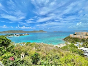 Un resort costero con aguas turquesas cristalinas, exuberante vegetación y vistas a islas distantes.
