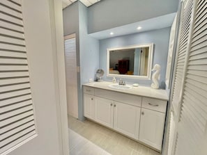 Un baño con tocador blanco, un espejo grande y un lavamanos.