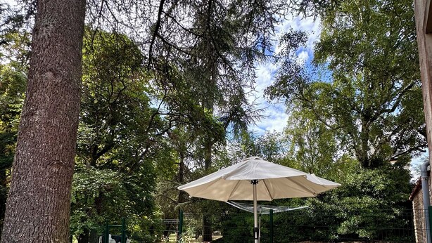 A patio area with a table and chairs under a canopy, surrounded by a brick patio and a fence.